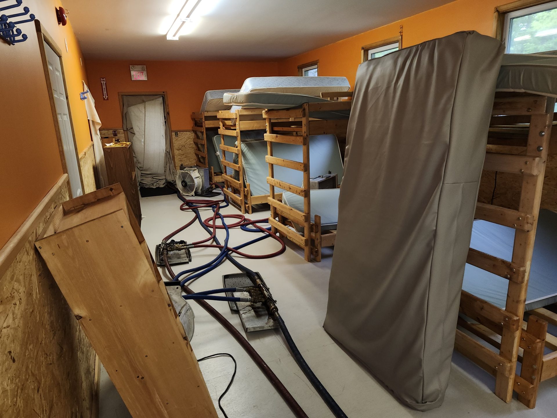 Bunk room during bed bug heat treatment, with mattresses upright and hoses connected to heating equipment.